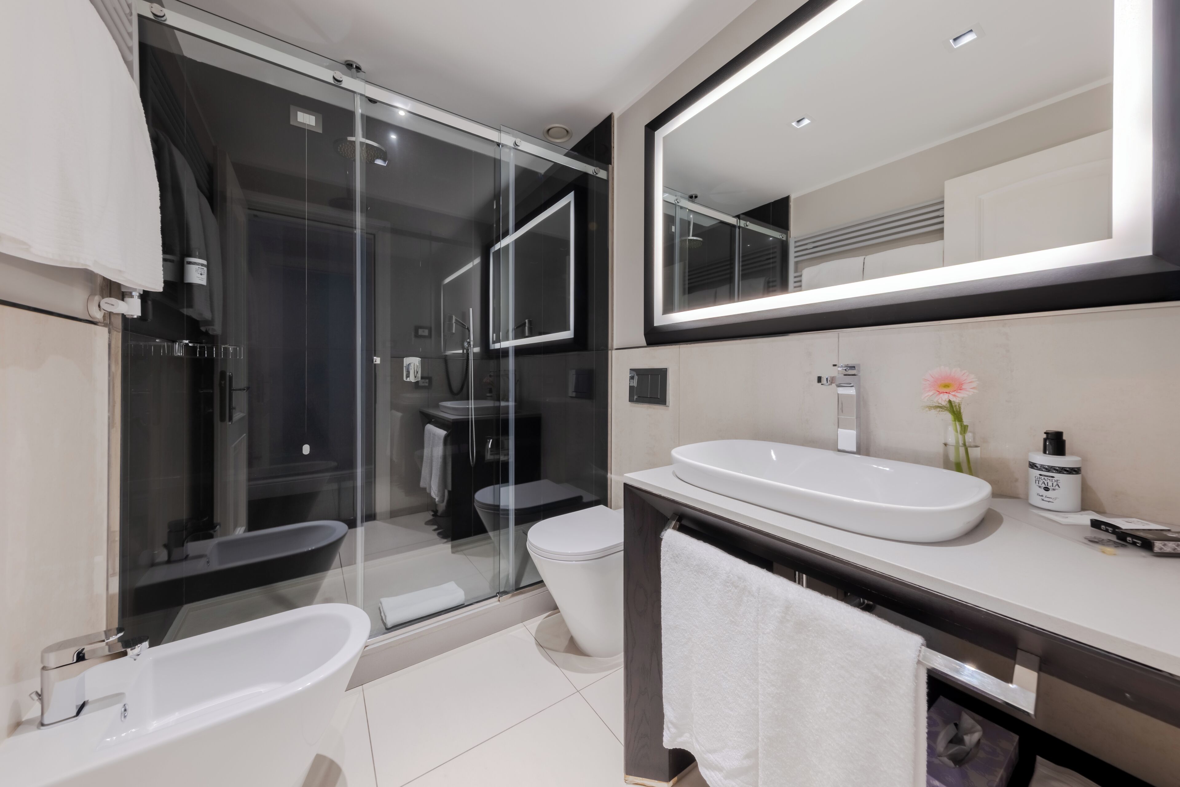 Une salle de bain moderne avec une douche à parois de verre, une baignoire blanche, un lavabo avec un miroir au-dessus et des toilettes.