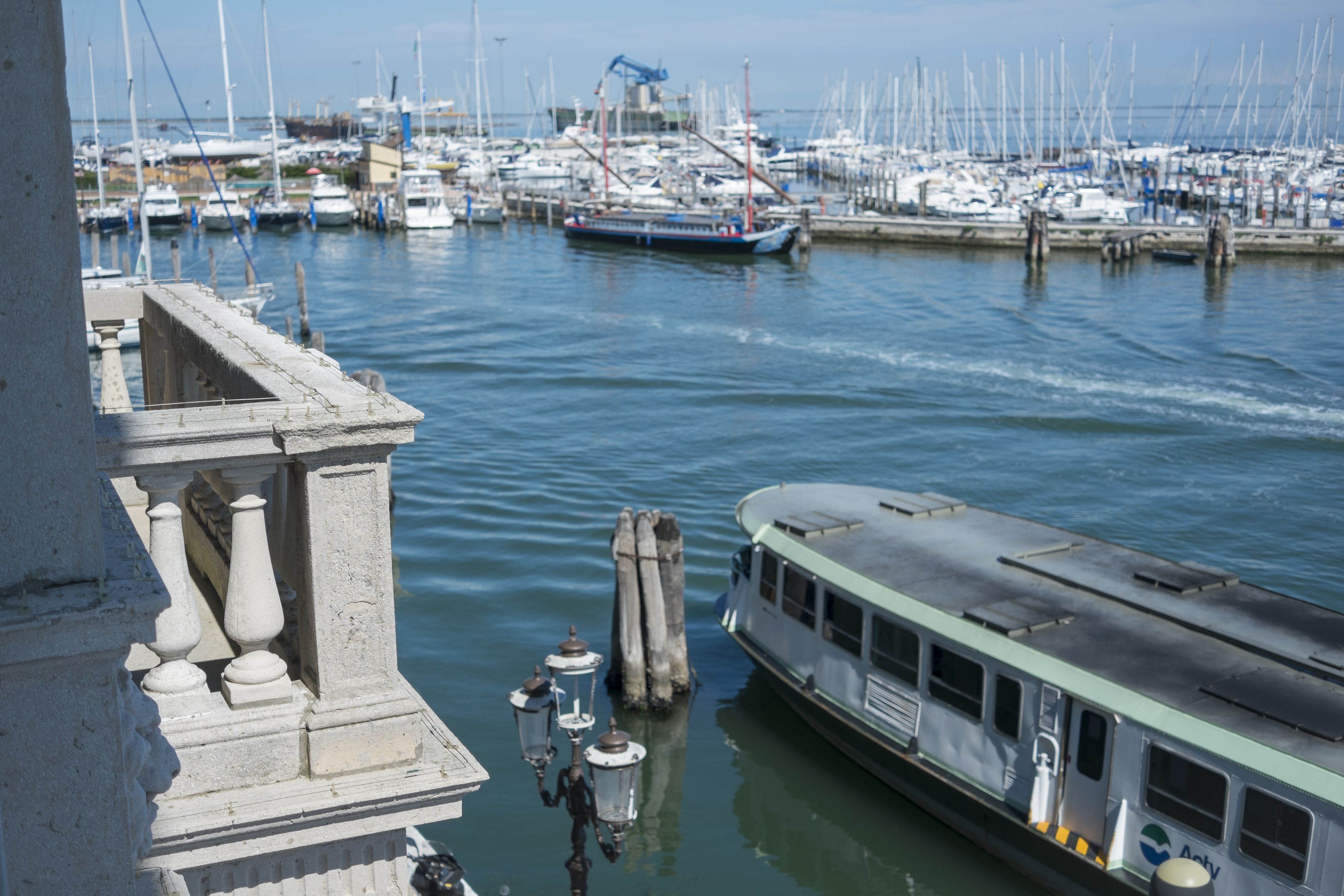 Un port de plaisance avec des bateaux amarrés, un ferry et un bâtiment à l’architecture classique.
