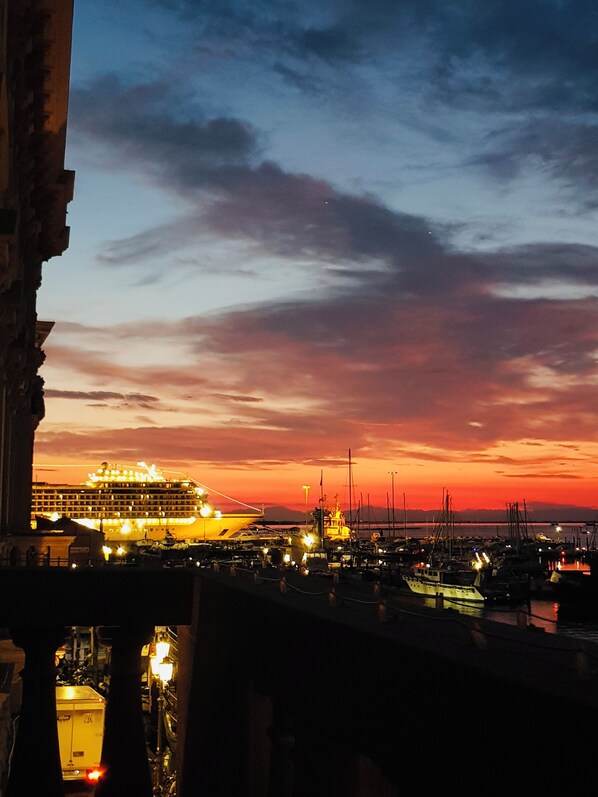 A sunset view from a balcony overlooking a marina with boats and a cruise ship. - Hotel Grande Italia (Chioggia)