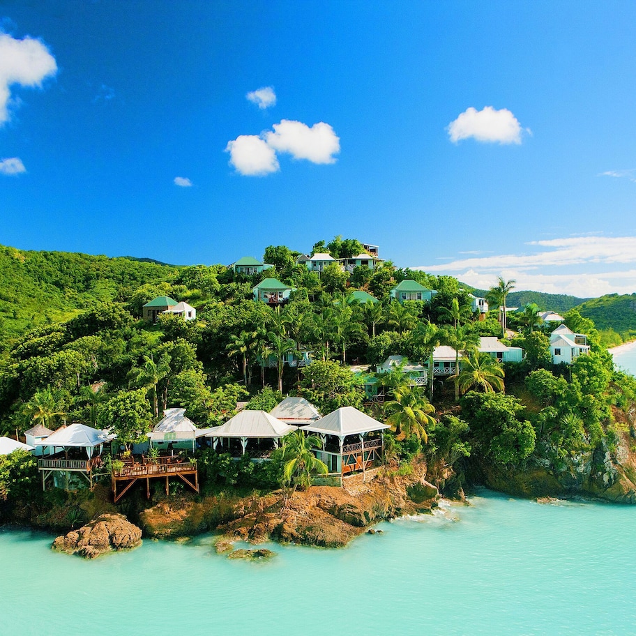 A tropical island resort with overwater bungalows, lush greenery, and a clear blue sea.