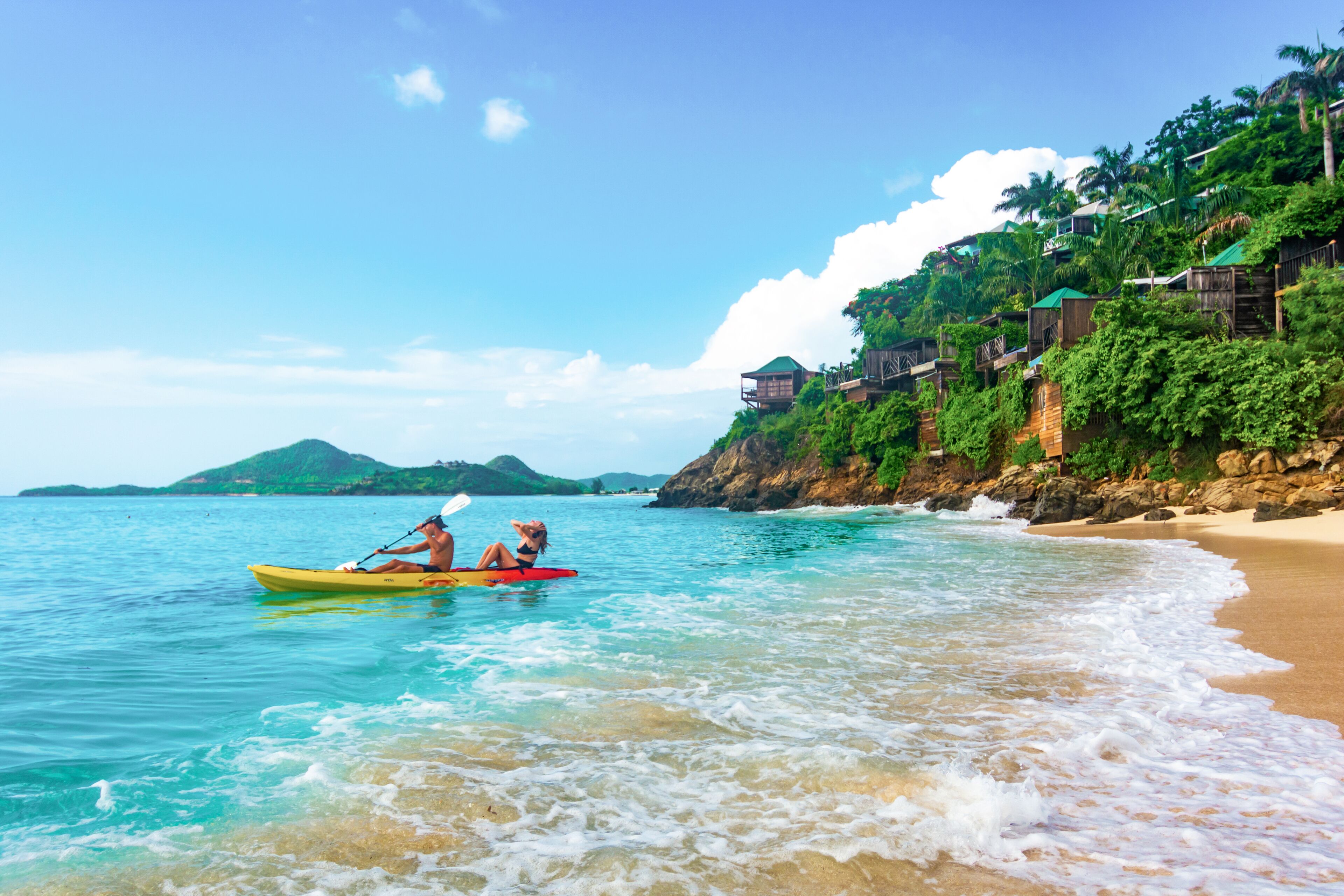 A beach with a kayak and a person in a swimsuit.