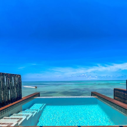 An infinity pool with a clear view of the ocean and a wooden deck.