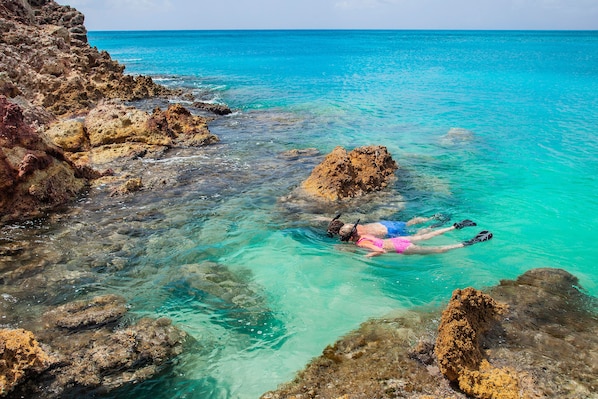 Na praia, areia branca, espreguiçadeiras, guarda-sóis 