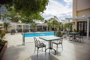 Zona de piscina en la azotea con asientos al aire libre y vista de un edificio al fondo.