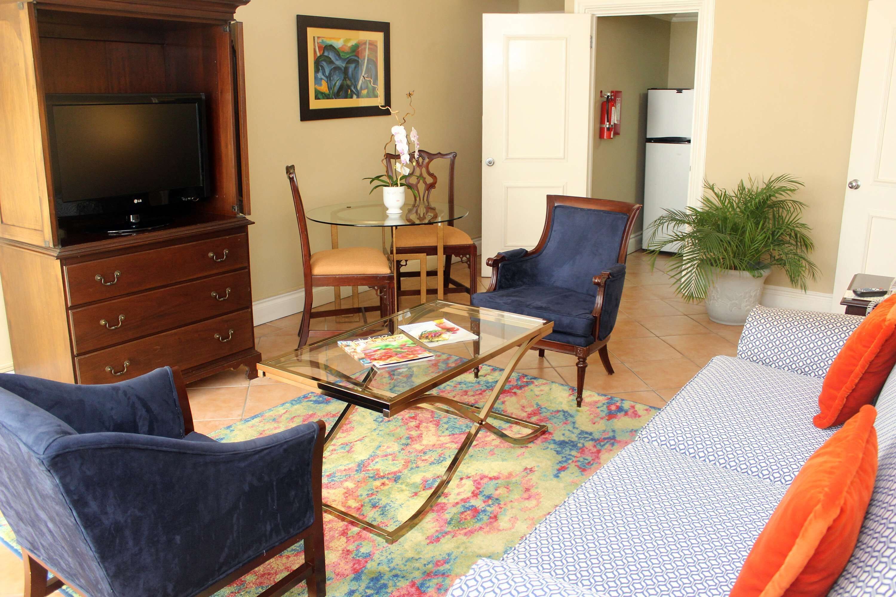 A living room with a TV, a glass coffee table, a sofa, and a chair.