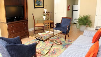 A living room with a TV, a glass coffee table, a sofa, and a chair.