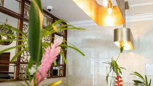 A reception area with a marble counter, hanging plants, and a modern pendant light fixture. - The Courtleigh Hotel and Suites (Kingston)