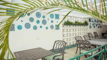 A dining area with tables and chairs, decorative wall patterns, and a green plant wall.