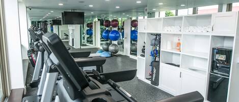A gym with treadmills, exercise balls, and a water dispenser.