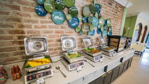 A buffet setup with various food stations, a brick wall, and decorative plates. - The Courtleigh Hotel and Suites (Kingston)