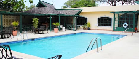 A pool area with a covered patio, outdoor seating, and a lifebuoy.
