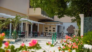 A hotel patio with outdoor seating, a palm tree, and a decorative wall. - The Courtleigh Hotel and Suites (Kingston)