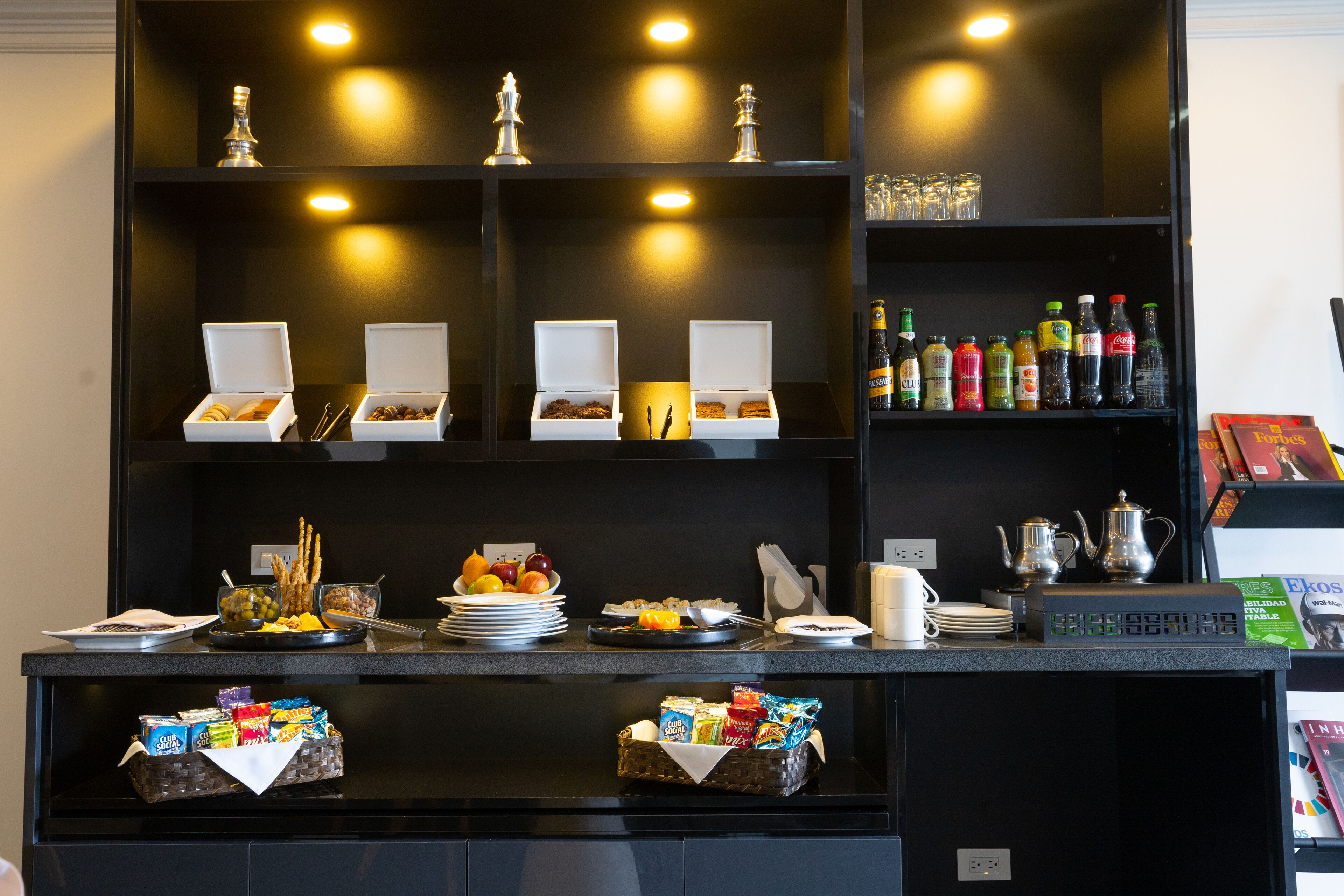 A buffet setup with various food items, beverages, and utensils.