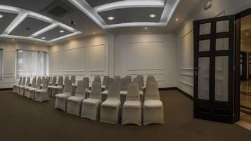 A conference room with rows of chairs, a projector screen, and a door with frosted glass panels.