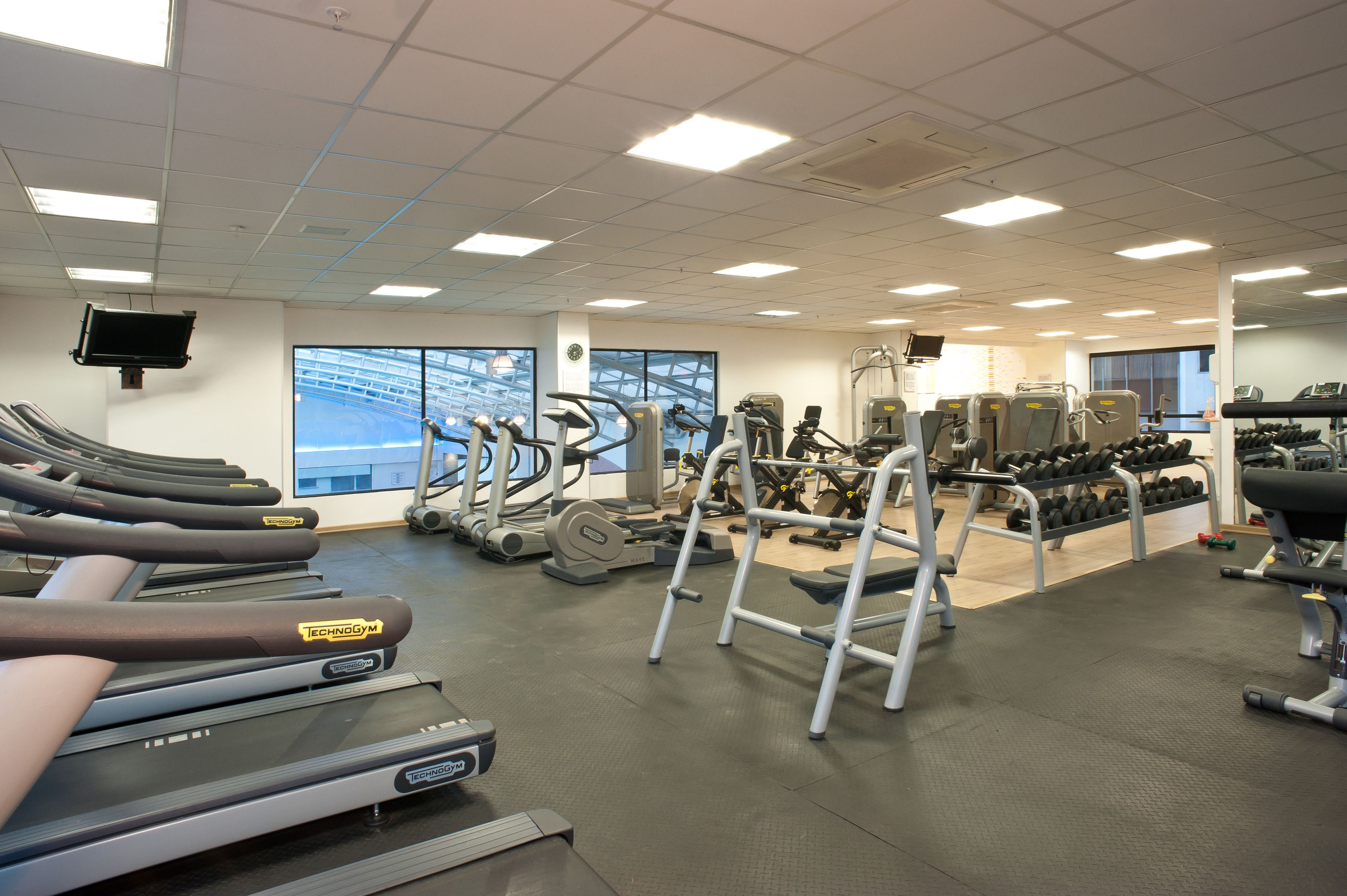 Un gimnasio con cintas de correr, elípticas y máquinas de pesas.