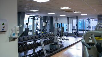 Ein Fitnessstudio mit unterschiedlichen Trainingsgeräten, darunter Kurzhanteln und Kraftmaschinen.