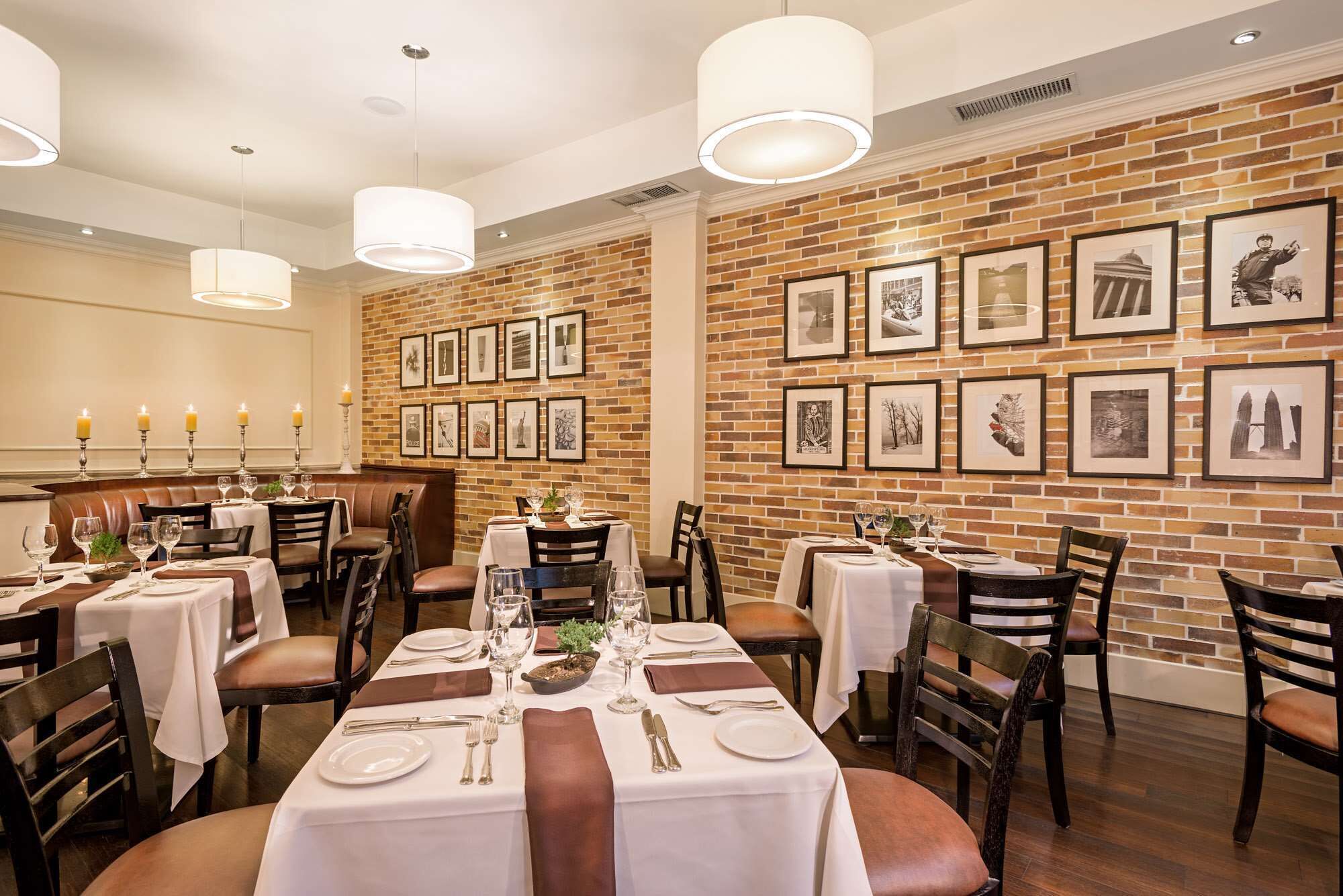 A restaurant with brick walls, framed pictures, and tables set for dining.