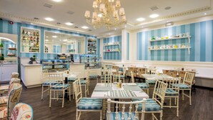 Un restaurante con una decoración azul y blanca, sillas de madera con cojines azules y una araña de techo.