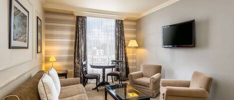 A living room with a sofa, armchairs, a coffee table, a TV, and a dining area with a table and chairs.