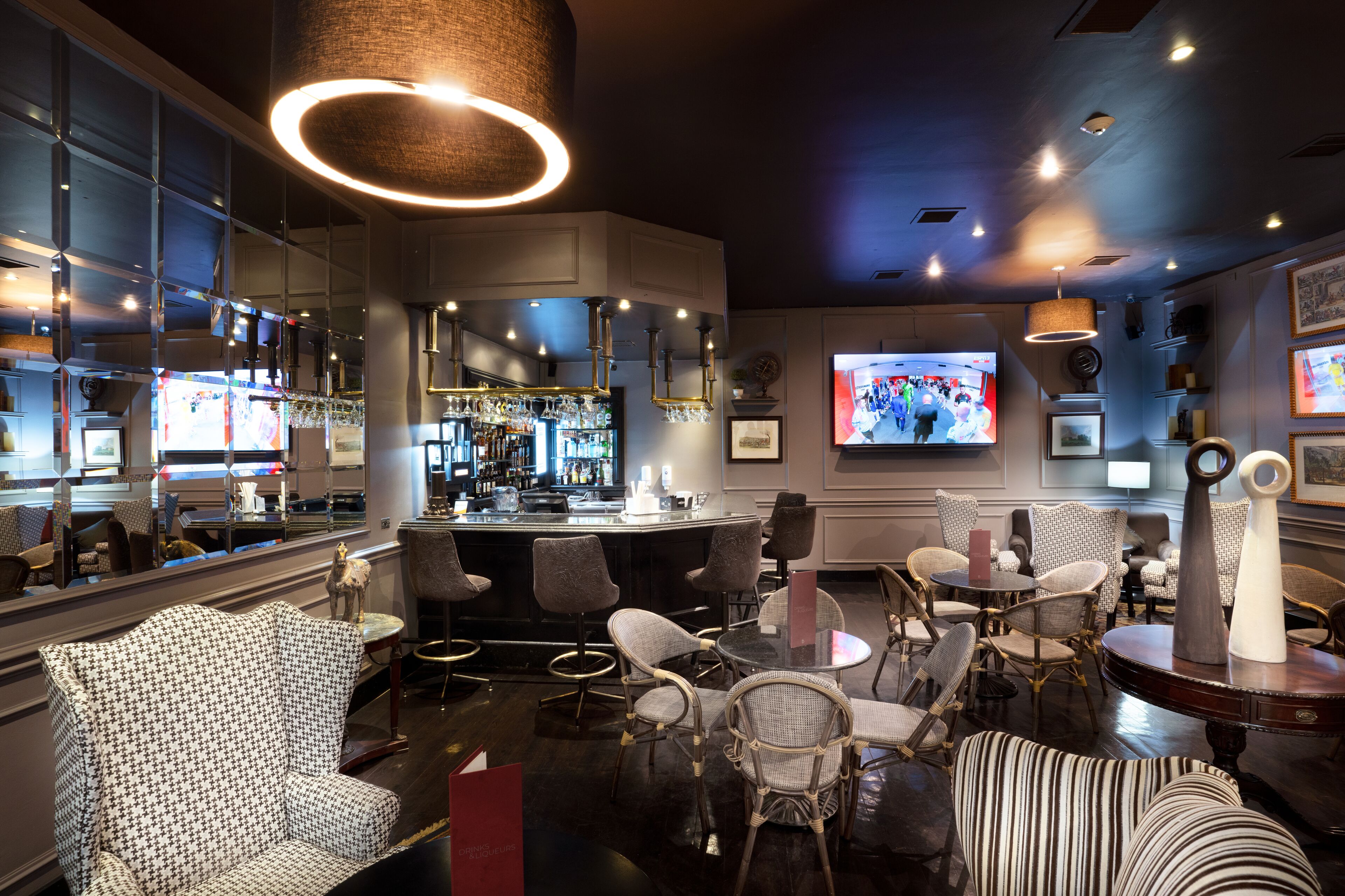 A modern bar area with seating, a television, and a bar stocked with bottles.