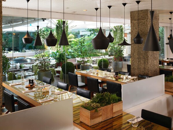 An outdoor dining area with tables, chairs, hanging pendant lights, and potted plants. - Sanderson London, a Morgans Originals hotel (London)