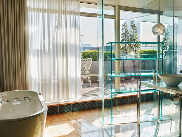 A modern bathroom with a glass shower enclosure, a white bathtub, and a glass shelving unit. - Sanderson London, a Morgans Originals hotel (London)