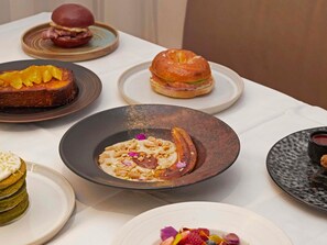 A table with various dishes, including a sandwich, a dessert, and a plate with a sauce.