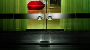 A modern hotel room with a large window, a red sofa, and a view of a building with a staircase. - Sanderson London, a Morgans Originals hotel (London)