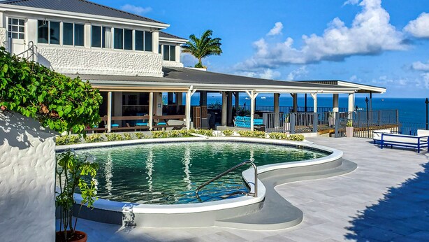 Un complexe hôtelier doté d’une piscine, d’un espace extérieur aménagé et offrant une vue sur l’océan.