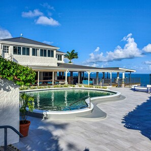 Un resort con piscina, mobiliario exterior y vista al océano.