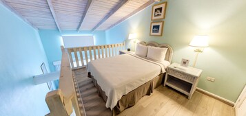 Un dormitorio con una cama, mesitas de noche, una lámpara, un marco de fotos y una escalera.