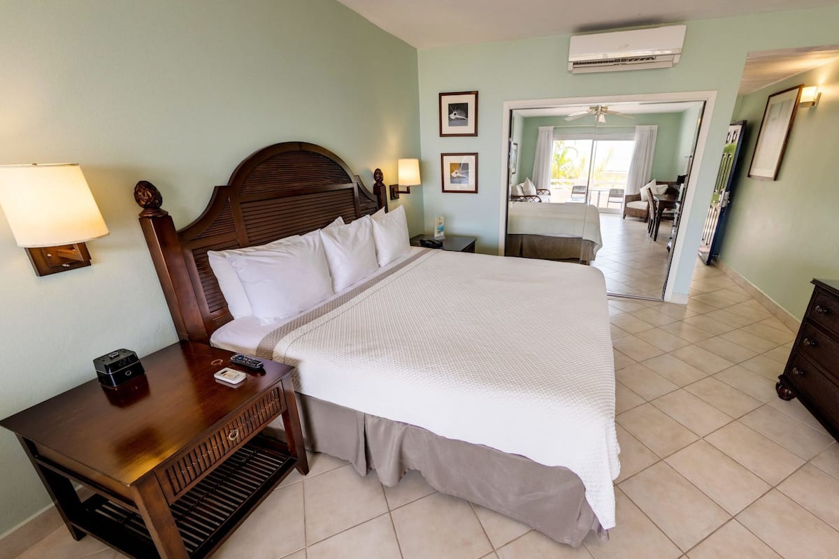 Une chambre d’hôtel avec un grand lit, des tables de chevet, une commode, une télévision et une porte donnant sur un balcon.