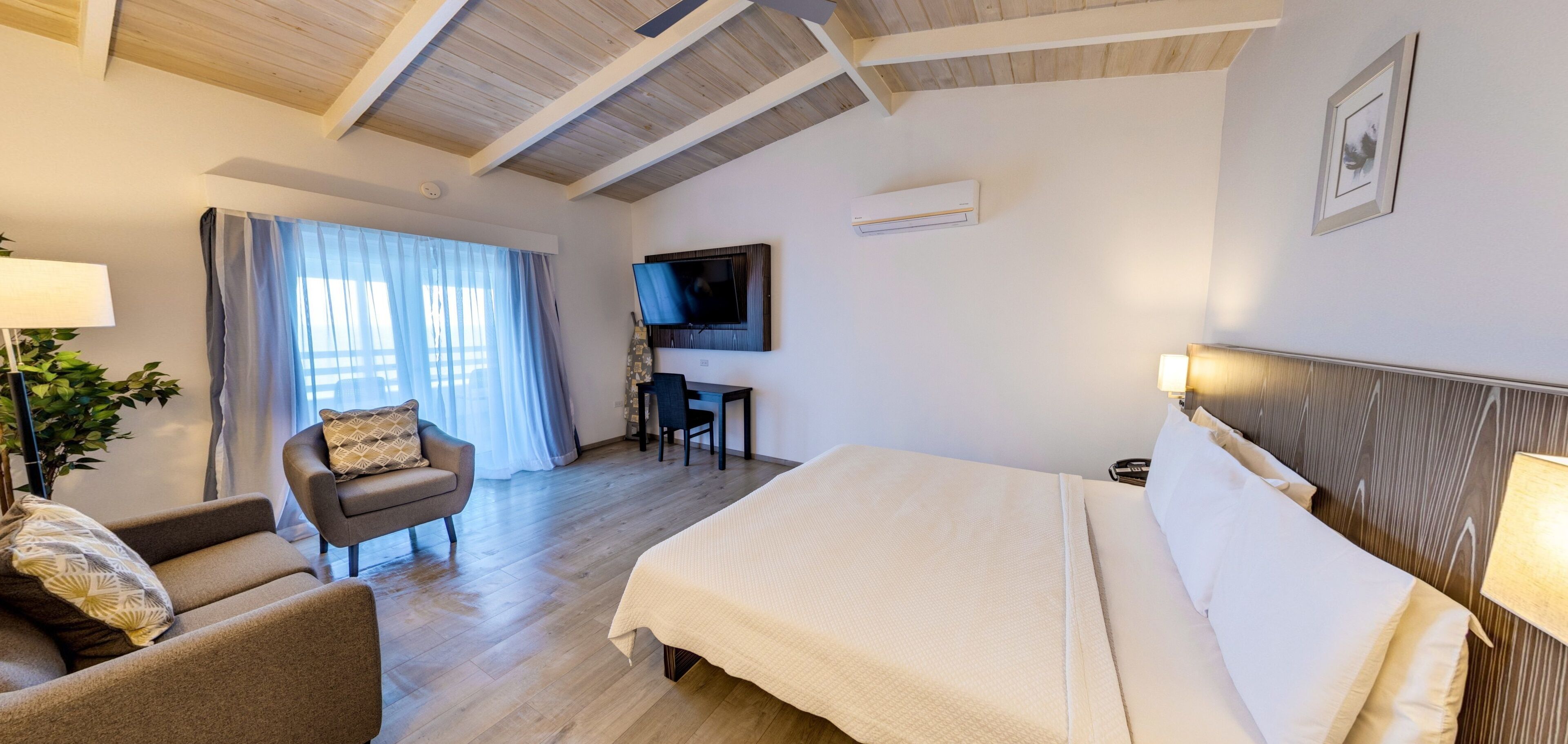 A hotel room with a bed, a desk, a TV, and a chair.