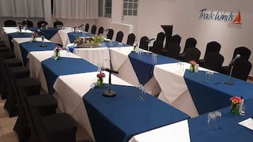 A conference room with long tables, chairs, and ceiling fans.