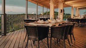 Un espace extérieur aménagé pour les repas, avec des tables en bois et des chaises en osier, offrant une vue sur un paysage pittoresque.