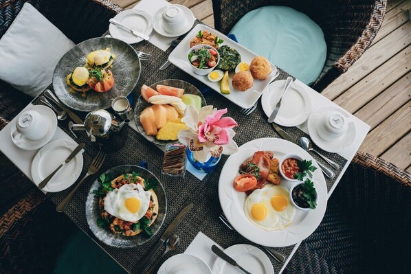A breakfast setting with various dishes, including eggs, toast, and pastries, arranged on a table with white plates and silverware.
