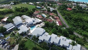 Vue aérienne d’un quartier résidentiel avec des maisons modernes, une piscine et une végétation luxuriante.