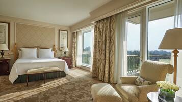 Una habitación de hotel con una cama grande, una zona de estar con una silla y una mesa, y un balcón con vistas.