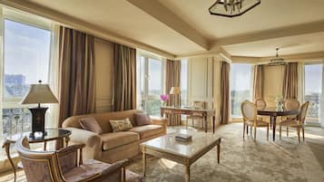 A spacious living area with a sofa, coffee table, and dining set. Large windows offer a view of the city.