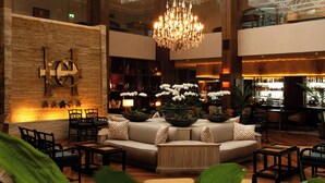 Een ruime lobby met een grote kroonluchter, zithoek en een bar.