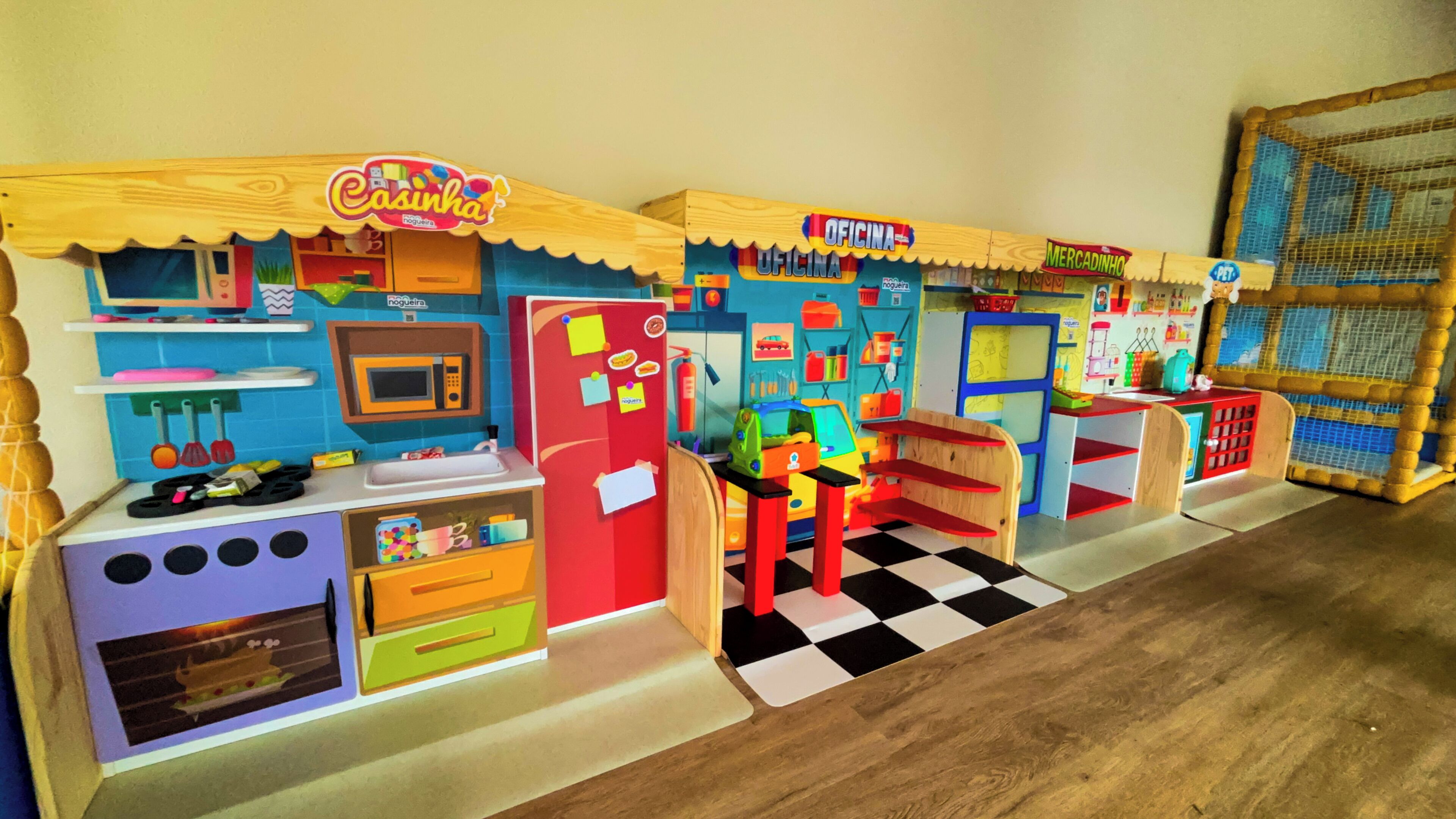 Eine bunte Kinderküche mit kariertem Boden, einem Kühlschrank, einer Mikrowelle und einem Spülbecken.