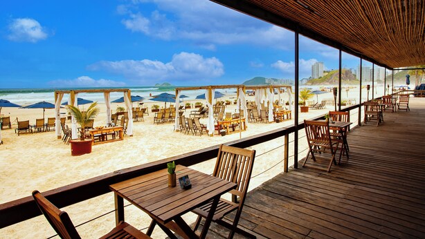 Een restaurant aan het strand met terras en uitzicht op de oceaan.