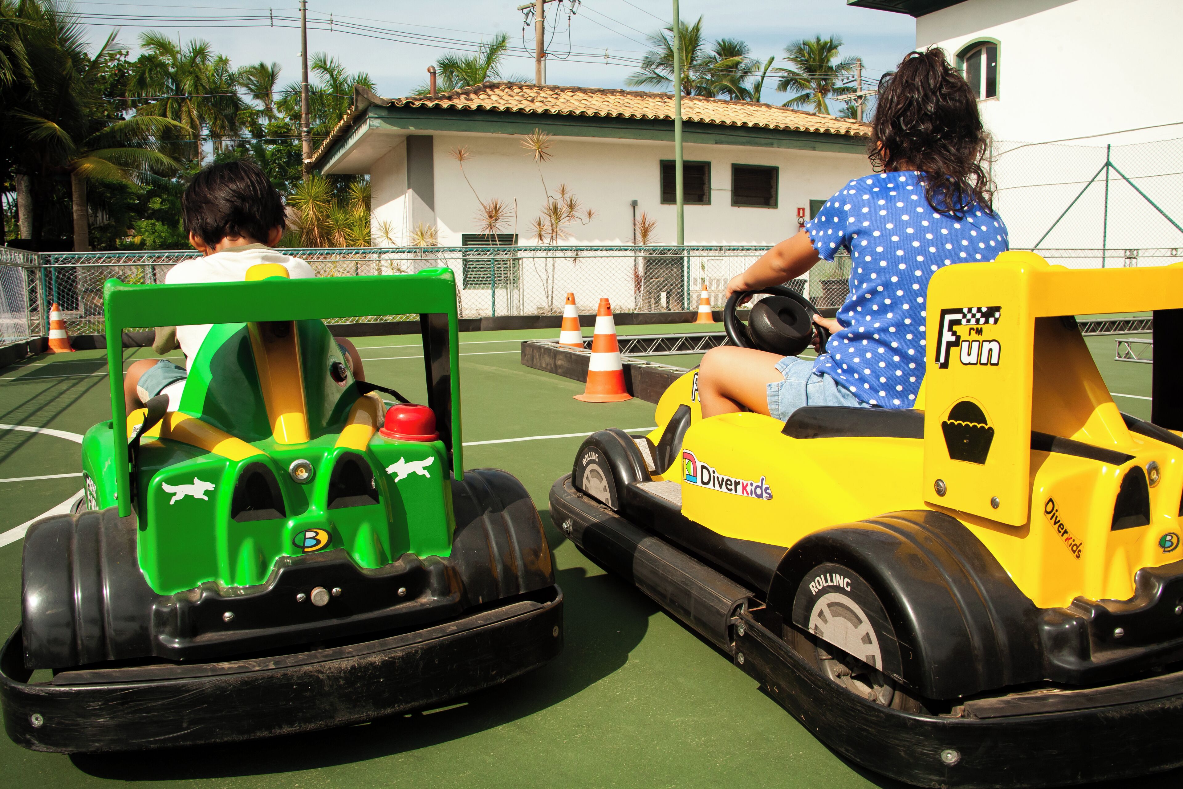 Two children driving bumper cars at an outdoor amusement park.
