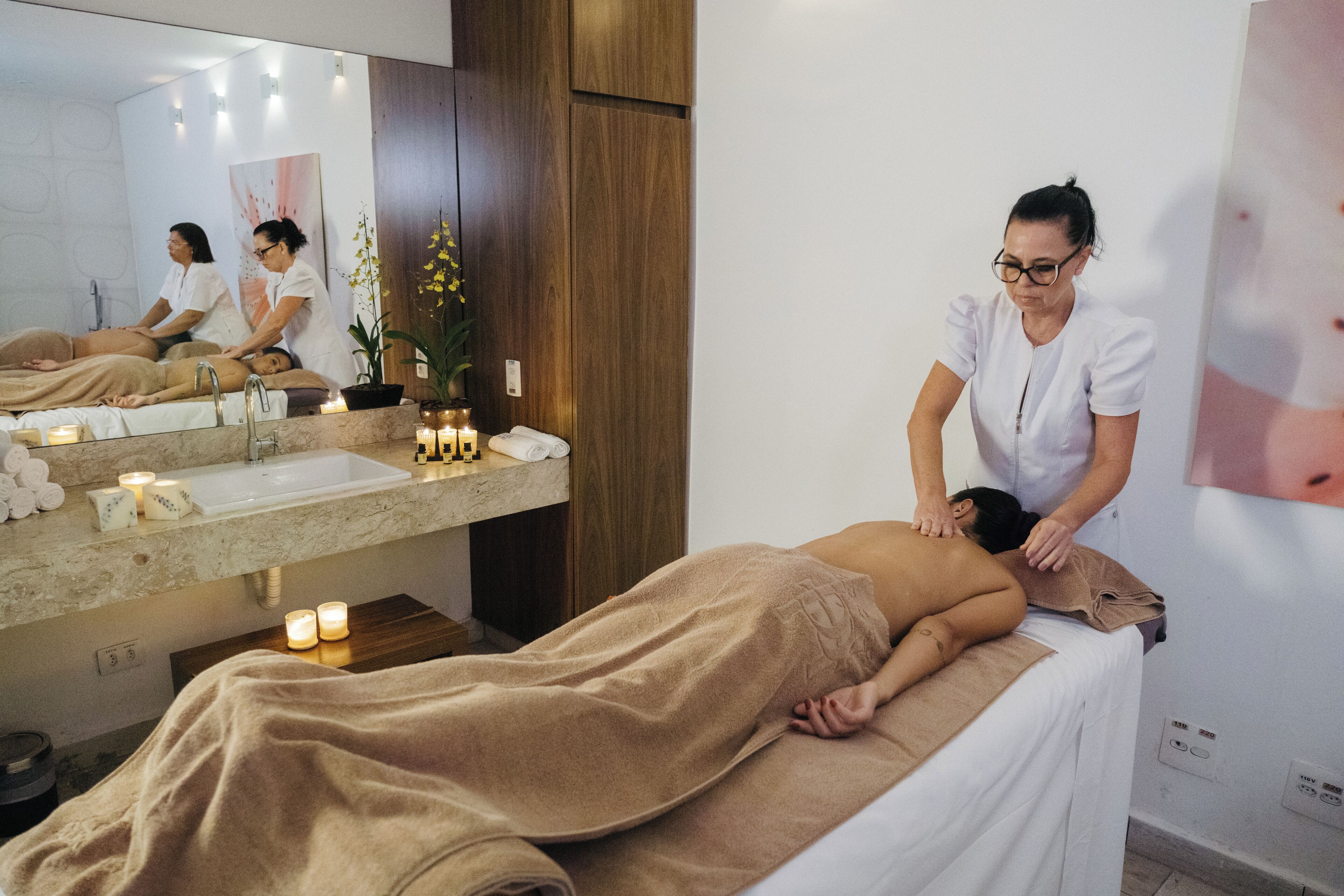 A massage therapy room with a bed, a sink, and candles.
