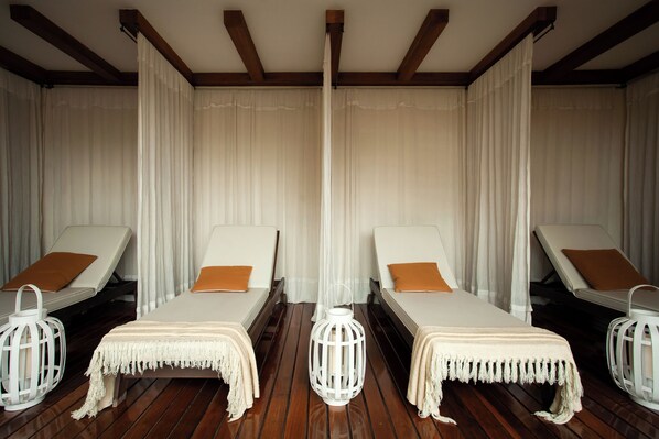 Una habitación con dos camas, cada una con dosel blanco, y suelo de madera.