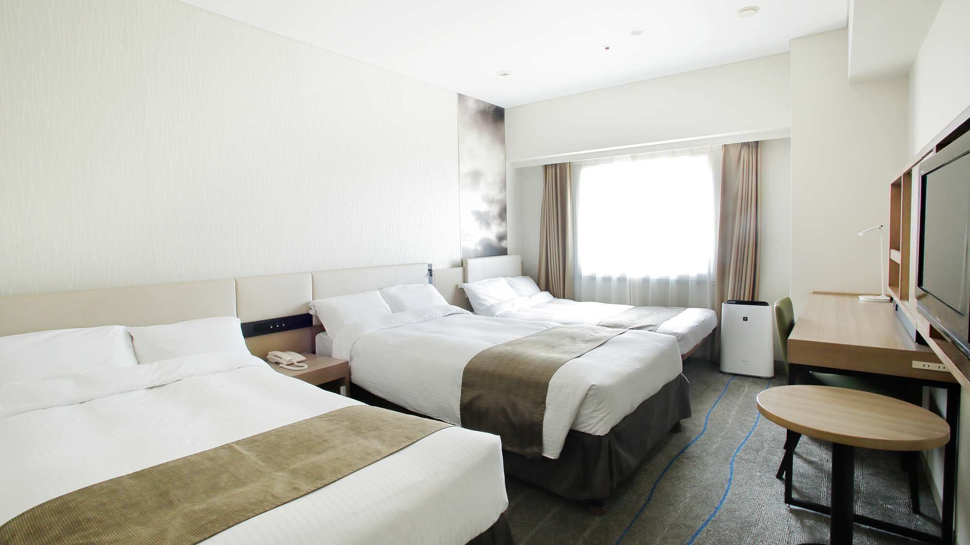 A hotel room with two beds, a desk, a TV, and a window with curtains.