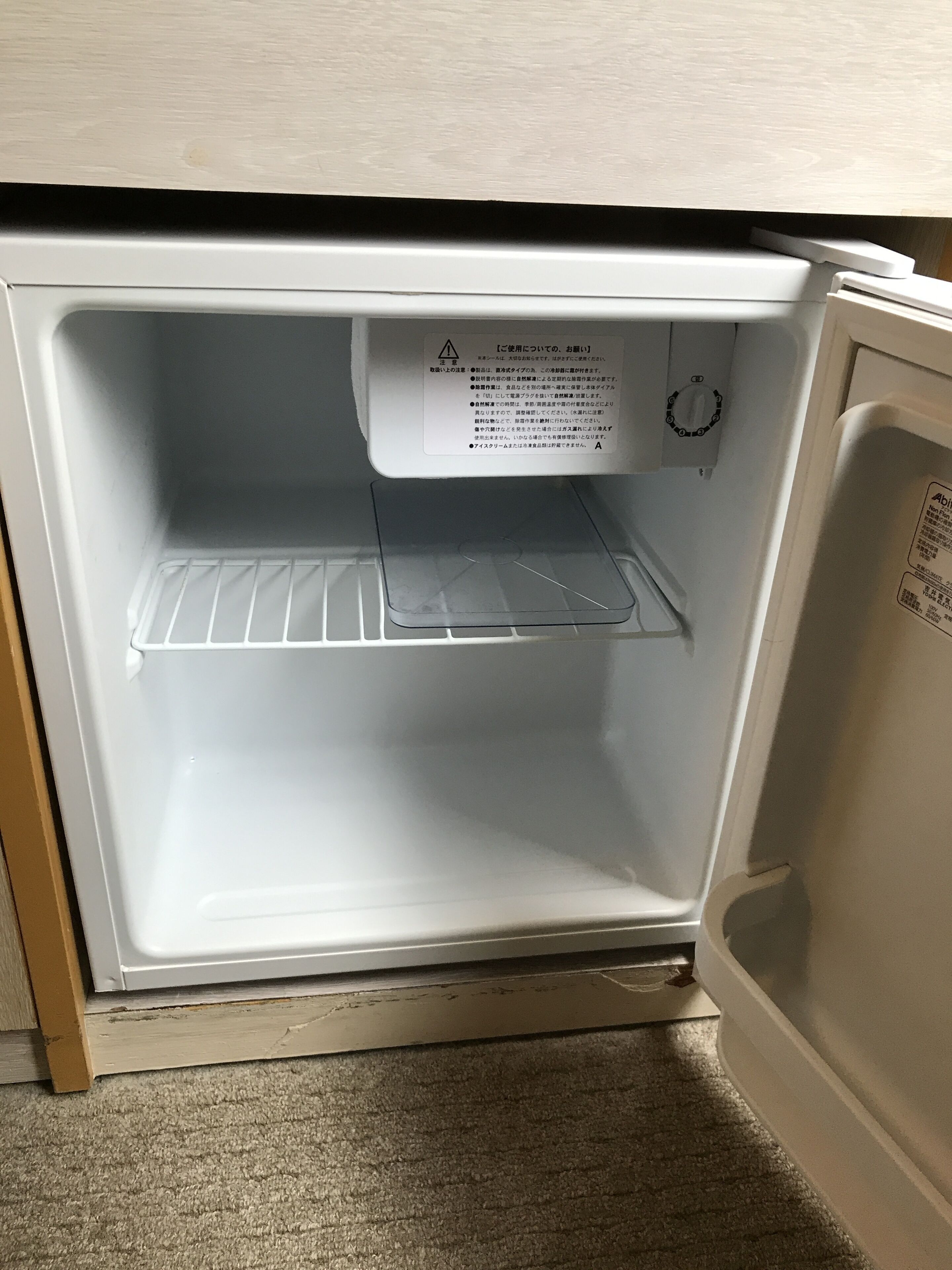 An open refrigerator with a warning label and a shelf inside.