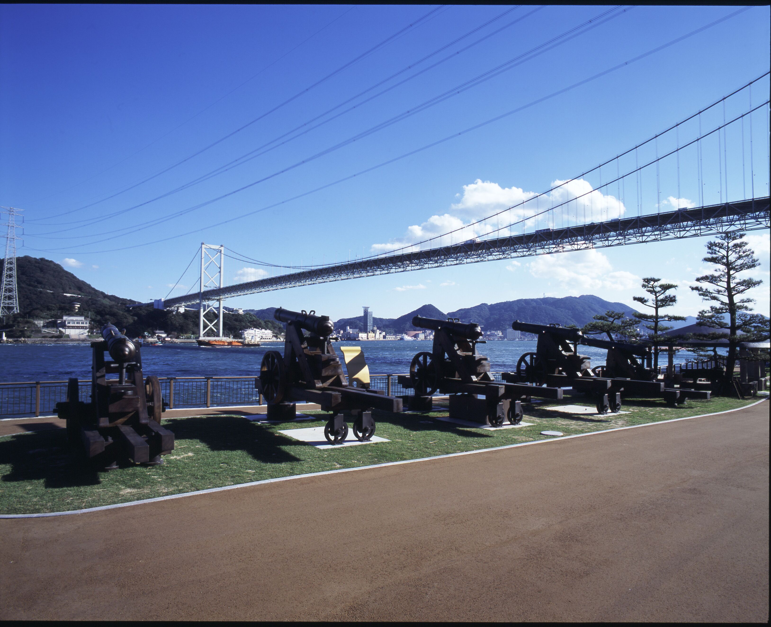 A park with cannons and a bridge in the background.