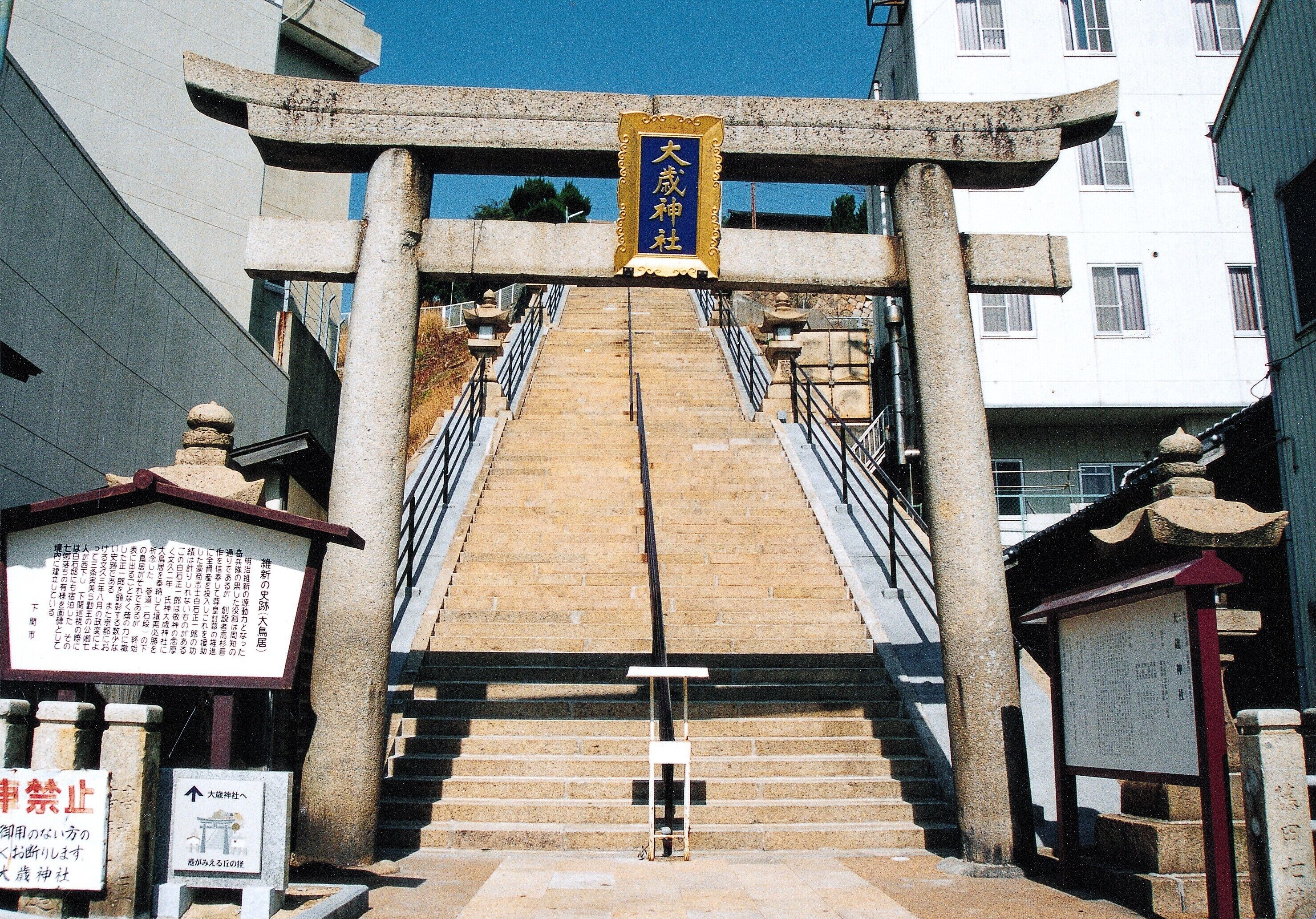 A stone staircase leading up to a traditional Japanese torii gate with a sign above it.