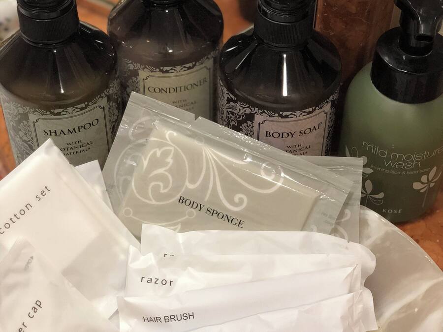 A collection of toiletries including shampoo, conditioner, body soap, body sponge, hair brush, and tooth brush.